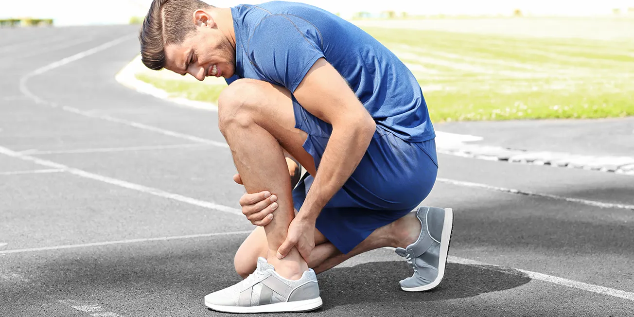 Mann med smerter i akilles.